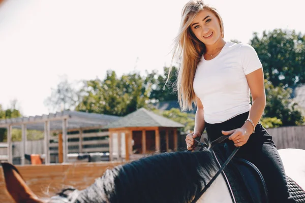 Elegante ragazza in una fattoria con un cavallo — Foto Stock