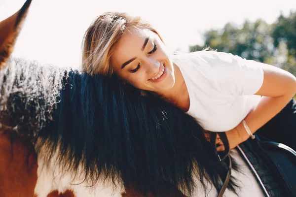 Elegante ragazza in una fattoria con un cavallo — Foto Stock