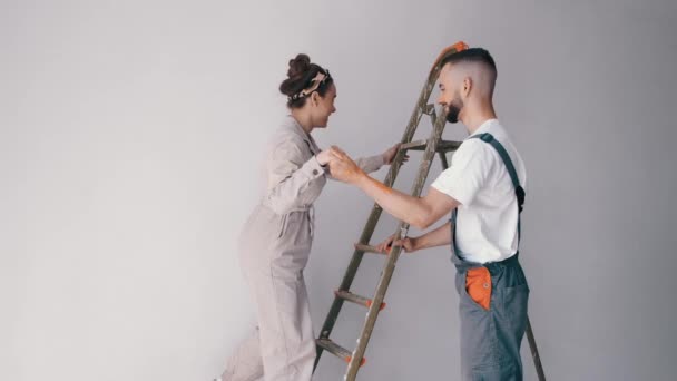 Felesége állt a létrán, míg férje fest a falon — Stock videók