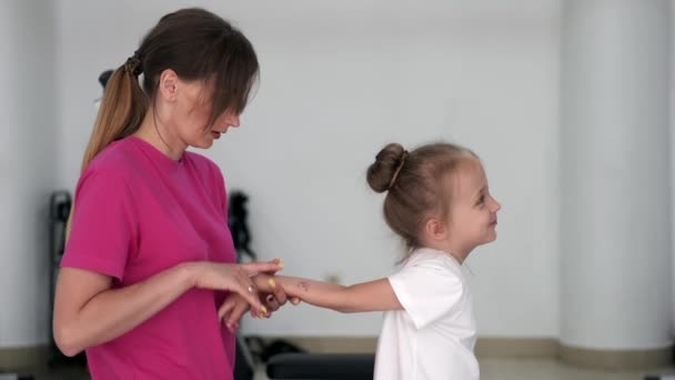 Mamma masserande liten flicka på gymmet — Stockvideo