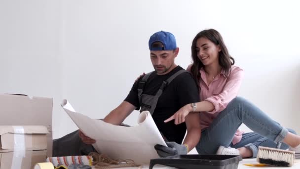 Paar kijken naar architectuur plannen voordat ze beginnen met hun renovatie — Stockvideo