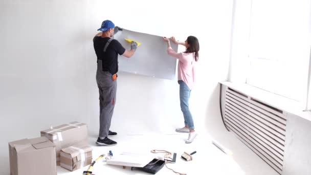 Couple hanging wallpaper on the wall — Stock Footage Couple hanging wallpaper on the wall Royalty Free Stock Footage