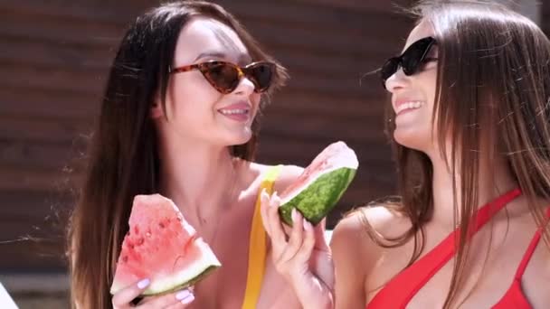 Dos chicas comiendo sandía junto a la piscina — Vídeos de Stock