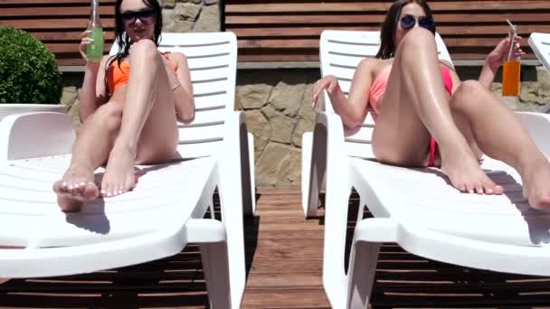 Две девушки, лежащие у бассейна — стоковое видео