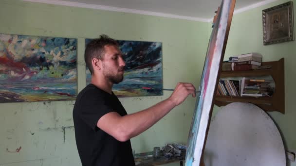 Artista masculino pintando un cuadro en un estudio — Vídeos de Stock