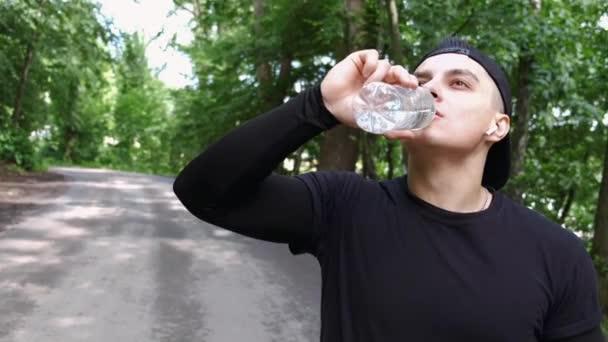 Fitter Mann trinkt nach einem Lauf und Workout draußen Wasser — Stockvideo