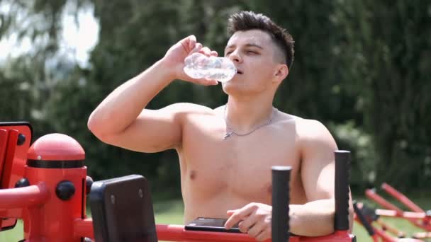 Uomo in forma bere acqua all'esterno dopo un allenamento — Video Stock