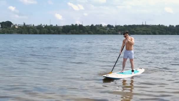 Fit man paddleboarding outside on the lake — Stock Video