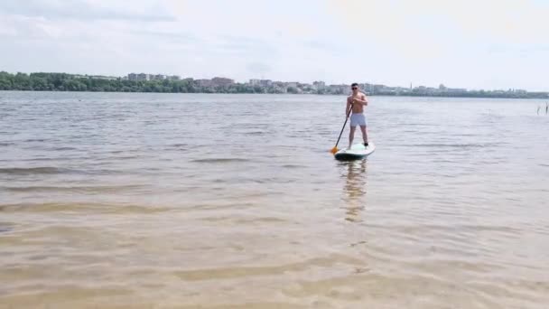 Fit Man paddleboarding zewnątrz na jeziorze — Wideo stockowe