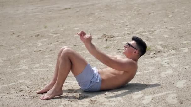 Homem apto a trabalhar fora e fazendo crunches na praia — Vídeo de Stock