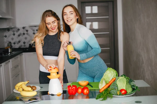 Two sports girl in a kitchen with vegetables