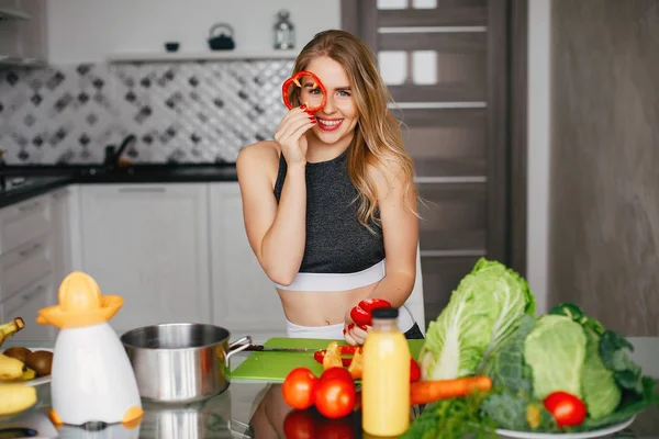 Sports girl in a kitchen with vegetables