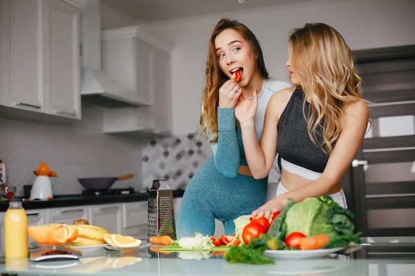 Dois esportes menina em uma cozinha com legumes — Fotografia de Stock