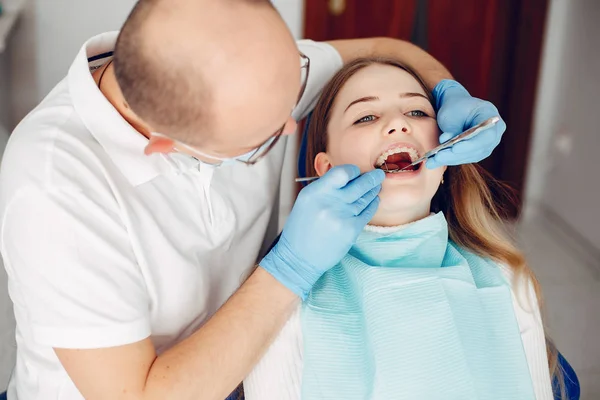 Schöne Mädchen sitzen in der Zahnarztpraxis — Stockfoto