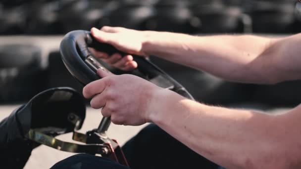 Atractivo hombre sititng en un gocart en la pista — Vídeo de stock