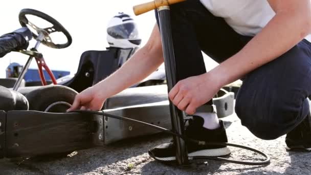 Homem atraente verificando a pressão do pneu em seu gocart — Vídeo de Stock