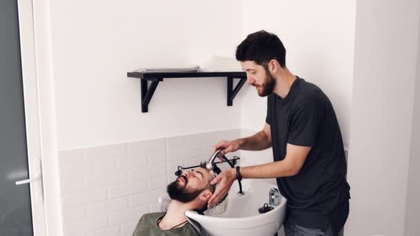 Barber washing clients hair in the sink at the hair salon — Stock Video