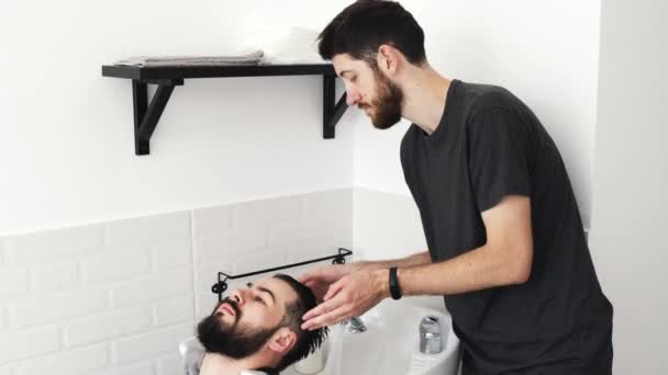 Barber washing clients hair in the sink at the hair salon — Stock Video