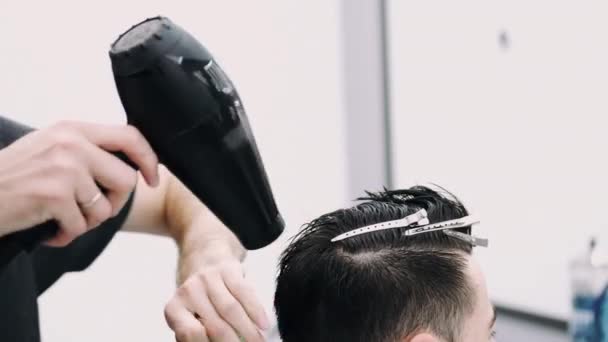 Atractivo hombre consiguiendo su pelo slyled y golpe seco — Vídeo de stock