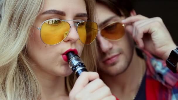 Stylish couple in a city. Two people use the electronic cigarette — Stock Video