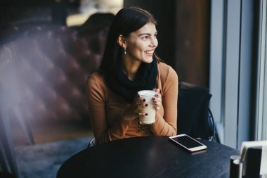 Esmer kız restoranda telefon kullanıyor.