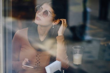 Esmer kız restoranda telefon kullanıyor.