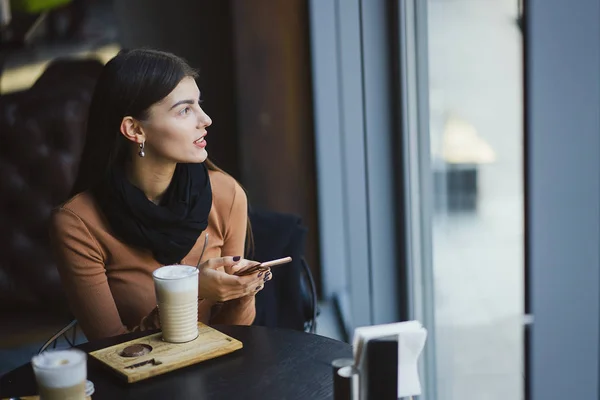 Brunetka dívka pomocí telefonu, zatímco v restauraci — Stock fotografie