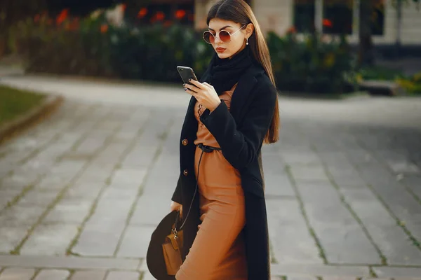 stylish girl walking through the city while using her phone