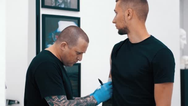 Tatoueur masculin tatouant un client — Video