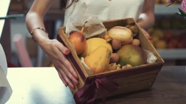 Флорист делает корзину фруктов для клиента в подарок — стоковое видео