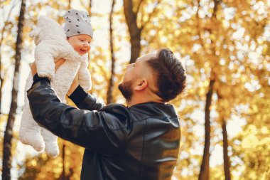 Sonbahar parkında oynayan sevimli bir aile.