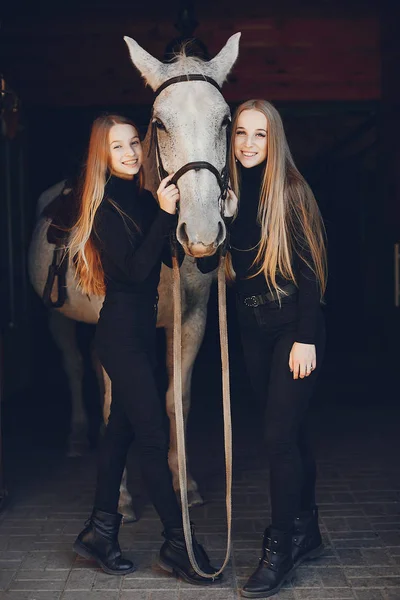 Elegante meisjes met een paard in een ranch — Stockfoto