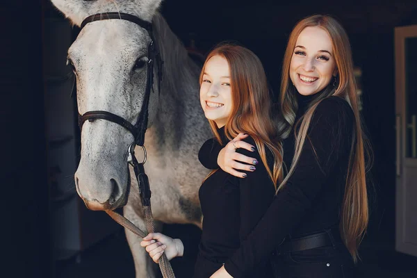 Meninas elegantes com um cavalo em um rancho — Fotografia de Stock