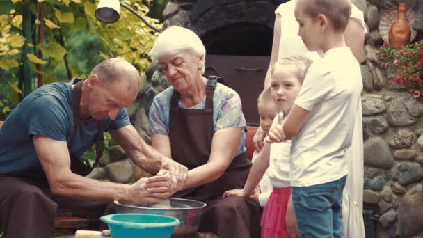 Prarodiče s vnoučaty dělají džbán v keramice — Stock video
