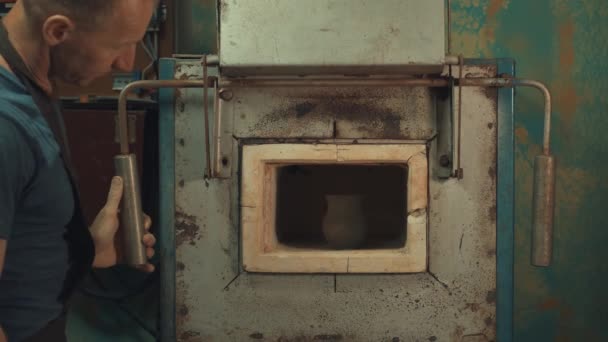 Mann legt einen Krug in einen Lehmofen — Stockvideo