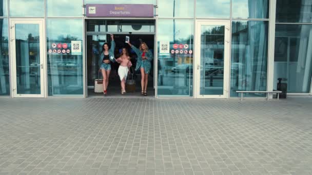 Девушки покидают аэропорт с чемоданами — стоковое видео