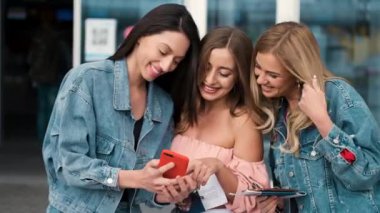 Cam kapılara yakın gülümseyen telefon ekranına bakan kızlar