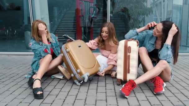 Meninas felizes sentadas perto do aeroporto com bagagem — Vídeo de Stock