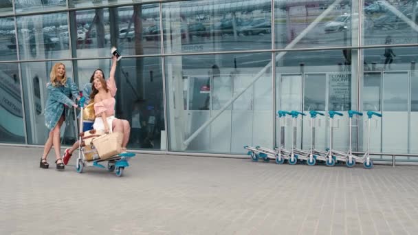 Flickor tittar på karta nära flygplatsen med resväskor — Stockvideo
