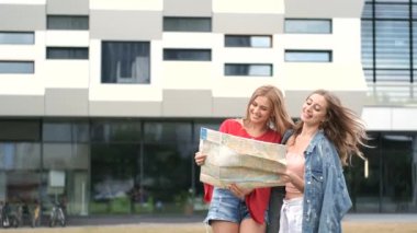 Modern binanın yanında duran harita tutan kızlar