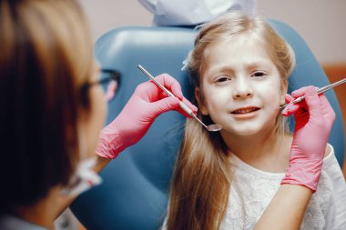 Sevimli küçük kız dişçi ofisinde oturuyor