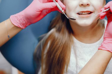 Sevimli küçük kız dişçi ofisinde oturuyor