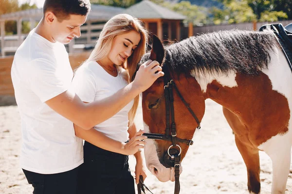 Beautiful couple spend time with a horses — Stock Photo, Image