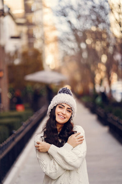 Cute brunette in a white sweater in a city