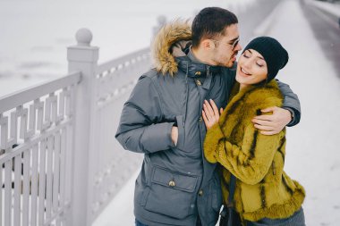 Güneşli bir kış gününde parkta yürüyen mutlu çift.