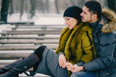 Güneşli bir kış gününde parkta yürüyen mutlu çift.