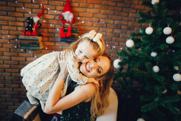 Madre e hija sentadas junto al árbol de navidad — Foto de Stock