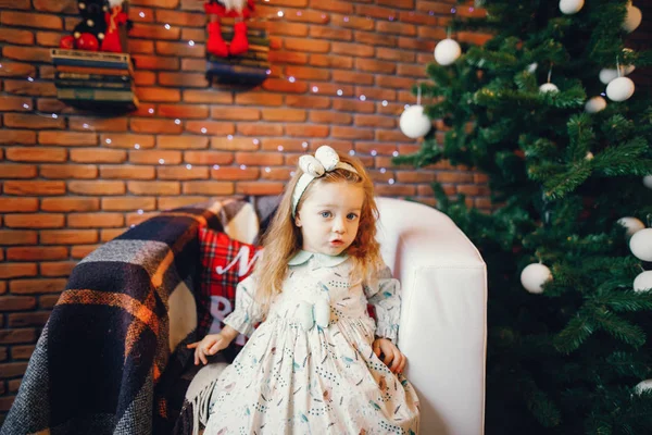 Blonde little girl sitting by the christmas tree Stock Picture