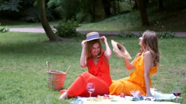 Şapka tutan ve parkta piknik yaparken kızlar