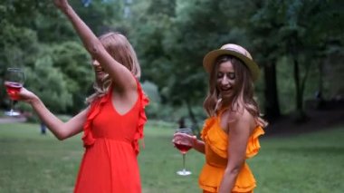 Elbiseli kız kardeşler dans ediyor ve şarap kadehleri tutuyorlar